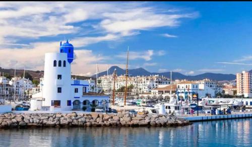 a white lighthouse in the water near a harbor at Acogedora Casa con terraza en Manilva in Manilva