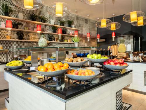 a buffet with bowls of fruit on a counter at Novotel Wien Hauptbahnhof in Vienna