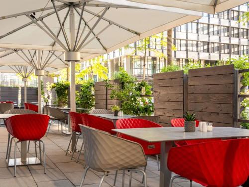 a restaurant with red chairs and tables and umbrellas at Novotel Wien Hauptbahnhof in Vienna