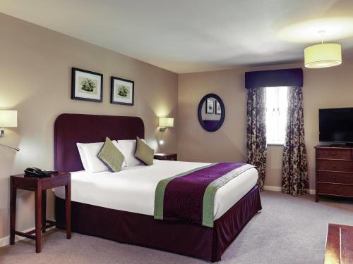 a hotel room with a bed and a television at Mercure Thame Lambert Hotel in Chinnor