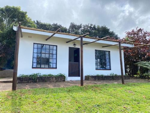 a small white house with a door in a yard at Luxury modern farm cottage with sea view in Southbroom