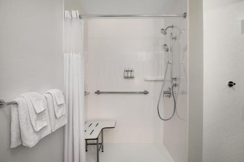 a white bathroom with a shower with white towels at Garner Hotel Paducah West in Paducah
