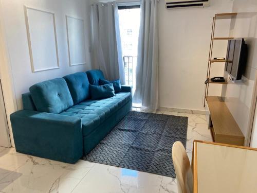 a blue couch in a living room with a television at Atlantico Flat Santos in Santos