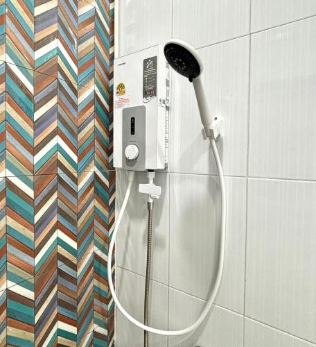 a shower with a hose attached to a wall at D sleep Home Chiangmai in Chiang Mai