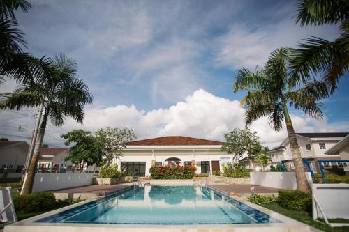 a swimming pool in front of a house with palm trees at Casa de Amor Modern Comfort across the pool in Dauis
