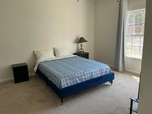 Un dormitorio con una cama con una manta azul y una ventana. en Saint Andrews 3BD & 2BTH, en Columbia