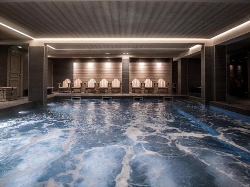 a swimming pool with chairs in a hotel lobby at Le Fitz Roy, a Beaumier hotel in Val Thorens