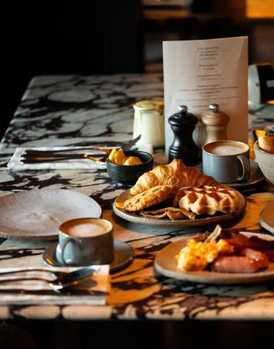 uma mesa com pratos de comida e chávenas de café em Le Fitz Roy, a Beaumier hotel em Val Thorens