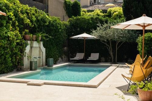 a swimming pool with two chairs and an umbrella at Le Moulin, Lourmarin, a Beaumier Hotel in Lourmarin