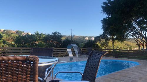 a table and chairs next to a swimming pool at Tríade Chalé da Canastra 2 in São Roque de Minas