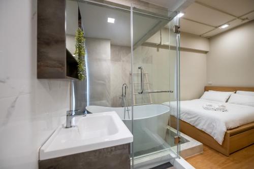 Un baño con bañera, lavabo y cama. en C2 stay Phayathai, en Pom Prap