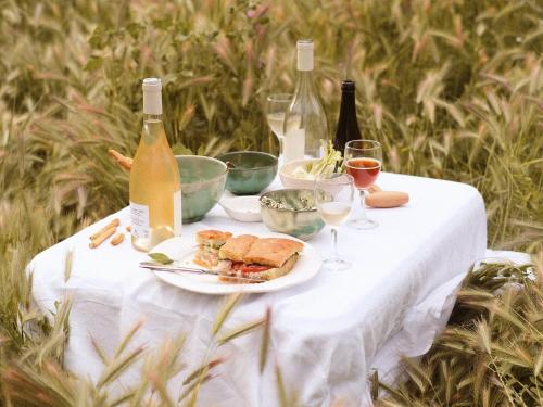 a table with a plate of food and bottles of wine at Le Galinier Lourmarin, a Beaumier Guesthouse in Lourmarin