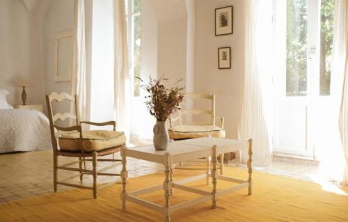 a room with two chairs and a table and a vase with flowers at Le Galinier Lourmarin, a Beaumier Guesthouse in Lourmarin