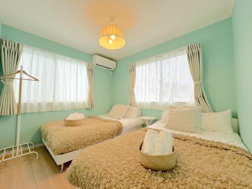 two beds in a room with blue walls and windows at THE FEEL ONNA 2 / Vacation STAY 18776 in Onna