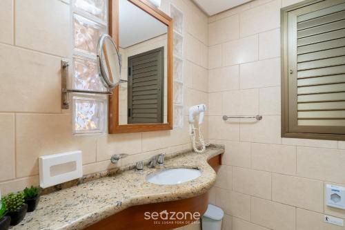 a bathroom with a sink and a mirror at Apto em Cond. c/ Piscina aquecida CUR0905 in Florianópolis