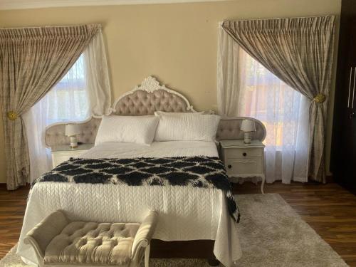 a bedroom with a large bed and two windows at Possiblerest Guesthouse in East London