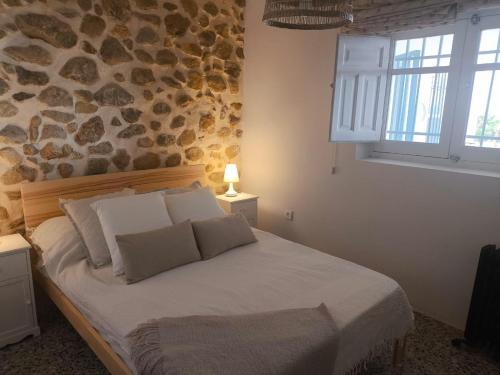 Un dormitorio con una cama con una pared de piedra. en Ca Leo, en Alicante