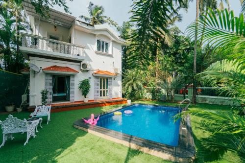 eine Villa mit einem Swimmingpool vor einem Haus in der Unterkunft Lavish 3bhk villa by bluewave hospitalty in Nagoa-Bardez