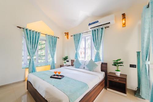 Schlafzimmer mit einem großen Bett und blauen Vorhängen in der Unterkunft Lavish 3bhk villa by bluewave hospitalty in Nagoa-Bardez