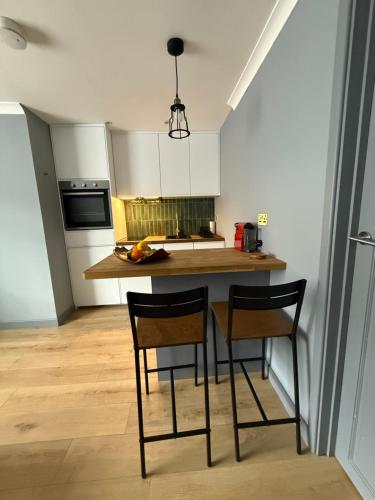 a kitchen with two chairs and a kitchen island at Modern 1 bedroom flat in Morden in Morden