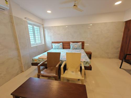 a bedroom with a bed and two chairs and a table at HOMESTAY NEAR AlRPORT - 3BHK , 1 BHK AND STUDIO in Chennai