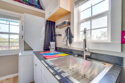 a kitchen with a sink and two windows at Galactikitty - Quirky Cabin Near Lake Brownwood! in Lake Brownwood