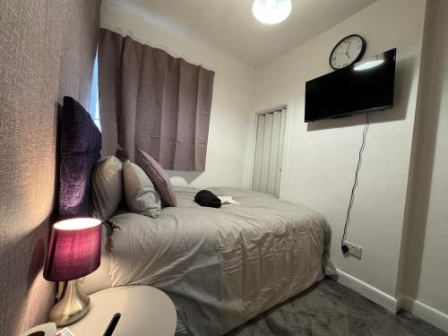 a bedroom with a bed with a clock on the wall at Bittern Lodge Homestay with Free Parking & Parking for cruise available, Full access to kitchen in Southampton in Southampton