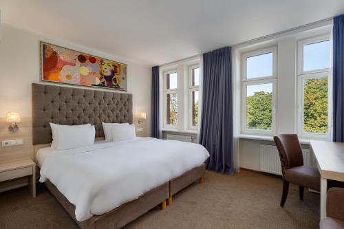 ein Schlafzimmer mit einem großen weißen Bett und Fenstern in der Unterkunft Radisson Hotel Old Town Riga in Riga