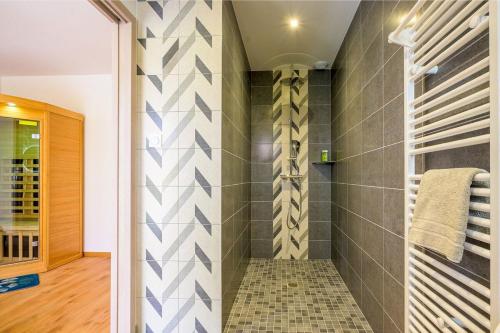 y baño con ducha de azulejos grises y blancos. en Ma bonne étoile, en Anould