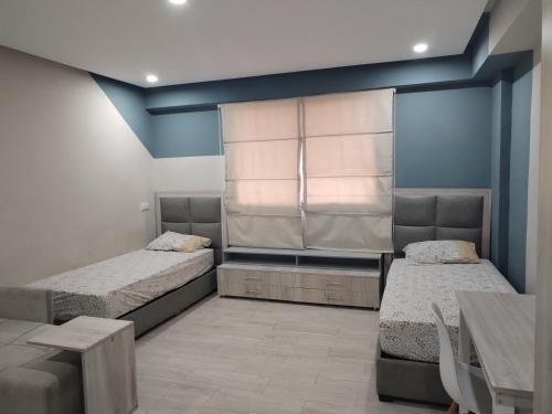 Dos camas en una habitación con ventana y mesa. en freehome oujda, en Oujda
