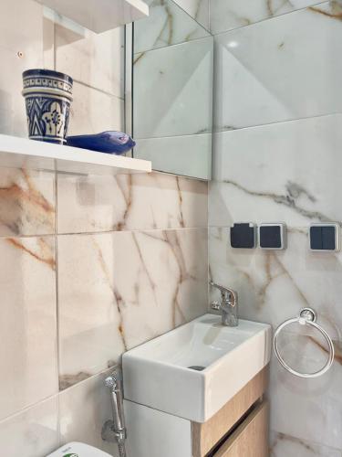 a white bathroom with a sink and a mirror at Chambre Agadir in Essaouira