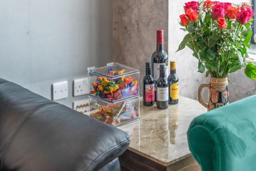 a table with bottles of wine and a vase of flowers at Brindley Apartment - City Centre - Free Parking, Fast Wifi and Smart TV by Yoko Property in Birmingham