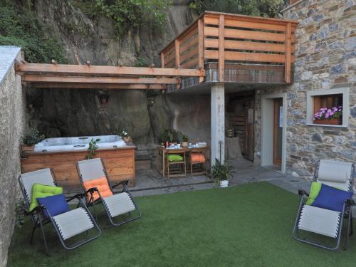 a patio with chairs and a hot tub and a deck at Green Chalet Scalotta - Nature Relax Lake view with Jacuzzi and Spa in Dervio