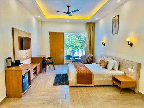 a hotel room with a bed and a desk and a tv at Creek Nest Resort in Rāmnagar