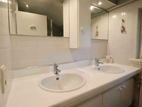 a white bathroom with two sinks and a mirror at Coeur de Biche in Rendeux