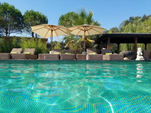 a swimming pool with chairs and umbrellas at Casa Bali Costa Brava in Llofríu