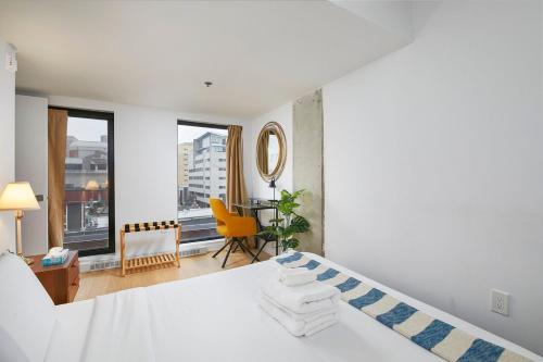 a bedroom with a white bed and a yellow chair at Chic Hideaway - Downtown Hotspot in Montréal
