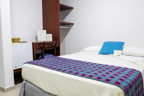 a bedroom with a bed with a blue pillow on it at Hotel Kamani Florencia in Florencia