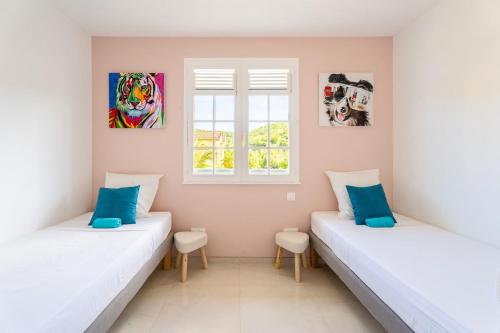 two beds in a room with two windows at Villa Rose Du Désert in Sainte-Anne