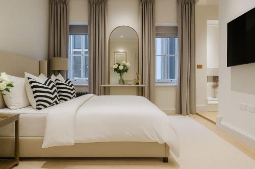 ein Schlafzimmer mit einem großen weißen Bett und einem Spiegel in der Unterkunft Premier 3 Bed Luxury Apartment in Covent Garden in London