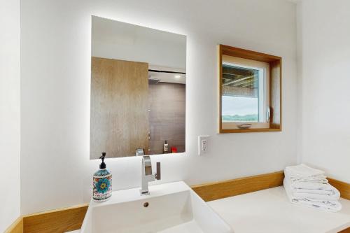 a white bathroom with a sink and a mirror at Intracoastal Indulgence in Holden Beach
