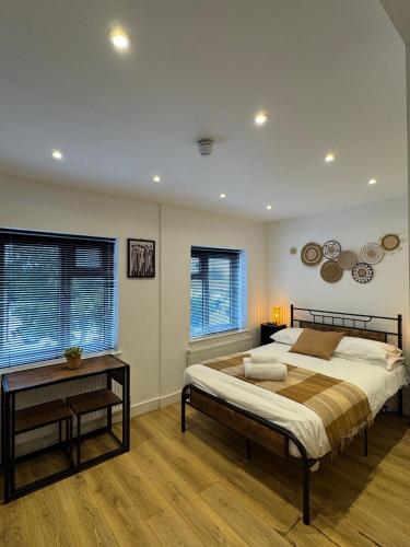 a bedroom with a bed and a table and windows at Townhouse Studio with Kitchen & Ensuite - Great Location in London