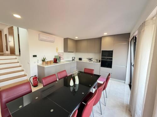 a kitchen and dining room with a black table and red chairs at Casa Brasão - Celorico de Basto in Celorico de Basto