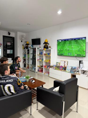 a group of people sitting in a room playing a video game at Global Beach Hostel - Ao Nang in Ban Khlong Haeng
