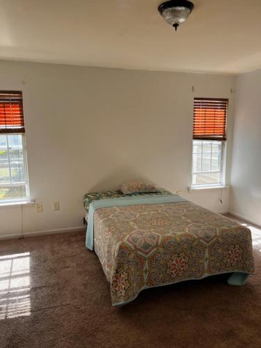 Un dormitorio con una cama y dos ventanas. en Cozy retreat room, en Charlotte