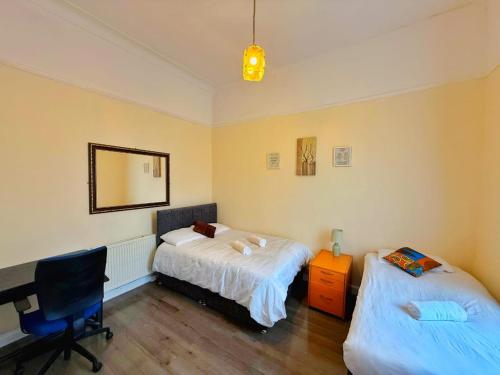 a bedroom with two beds and a desk and a mirror at Near City-Birkenhead rooms in Birkenhead