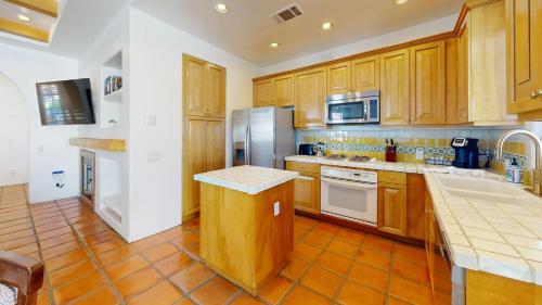 a kitchen with wooden cabinets and stainless steel appliances at SV253 2BR 3BA Spa Villa with Pool Access & Views in La Quinta