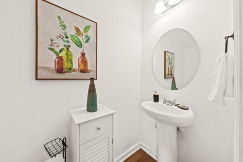 a white bathroom with a sink and a mirror at Southern Oak Cottage in Ladson