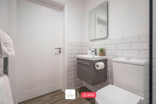 a white bathroom with a toilet and a sink at Beachside Retreat l Sun Terrace l Hot Tub l Free Parking l Seaside Escapes Short Lets & Serviced Accommodation in Bournemouth