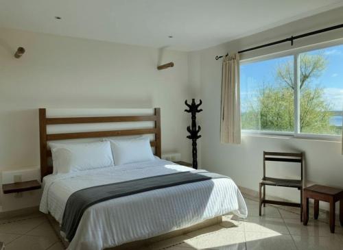 ein weißes Schlafzimmer mit einem Bett und einem Fenster in der Unterkunft Viajero Bacalar Hostel in Bacalar